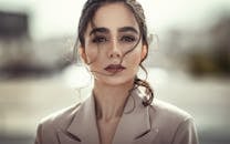 Stylish portrait of a woman with striking features, expressing confidence and elegance in an outdoor setting.